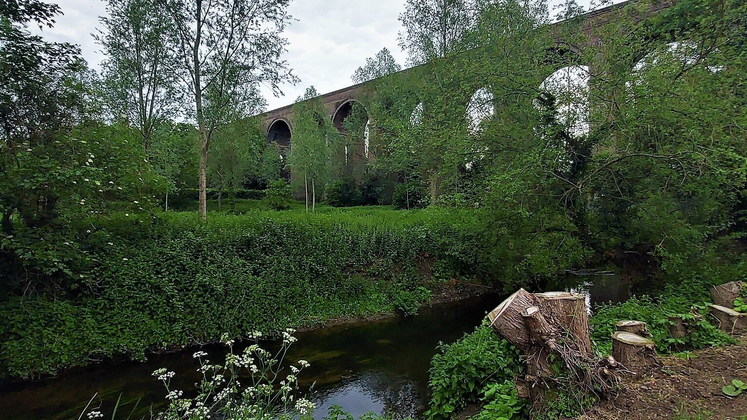 the arches of the chappel viaduct viewed across the river colne from the pub garden of the Swan Inn
